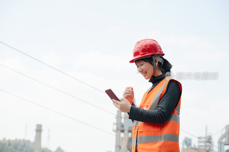 A female worker in a cement plant held a mobile phone and showed a very happy smile on her face